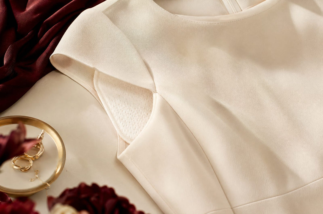 Zone d'aisselle d'une robe creme avec un coussinet absorbant discret, a plat